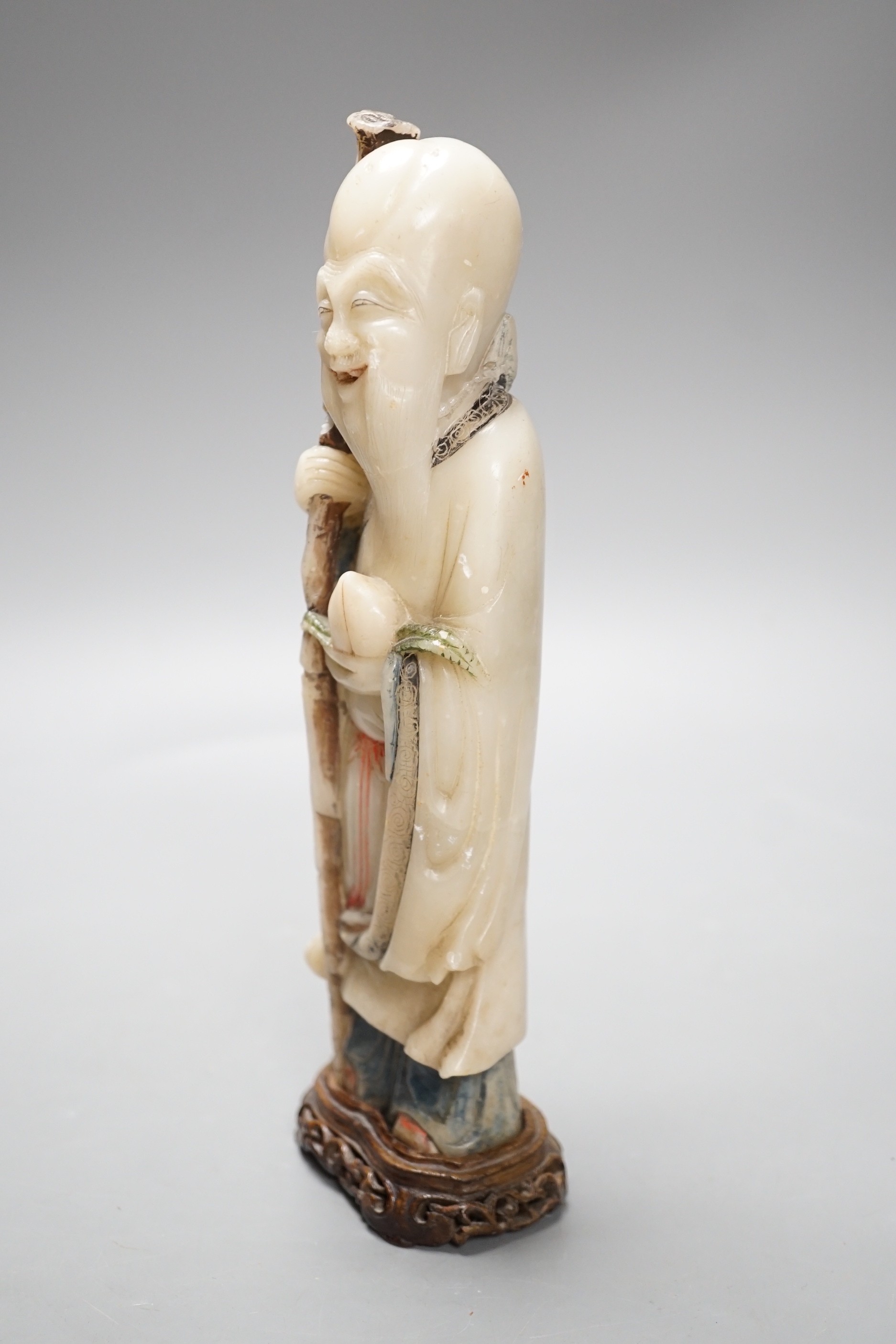 A 18th century Chinese carved soapstone figure of Shao Lou on carved hardwood stand. 24cm high.